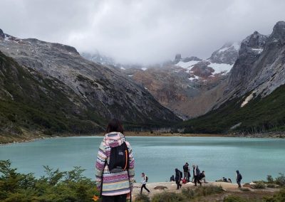 Laguna esmeralda mujer admirando la laguna con montañas atras