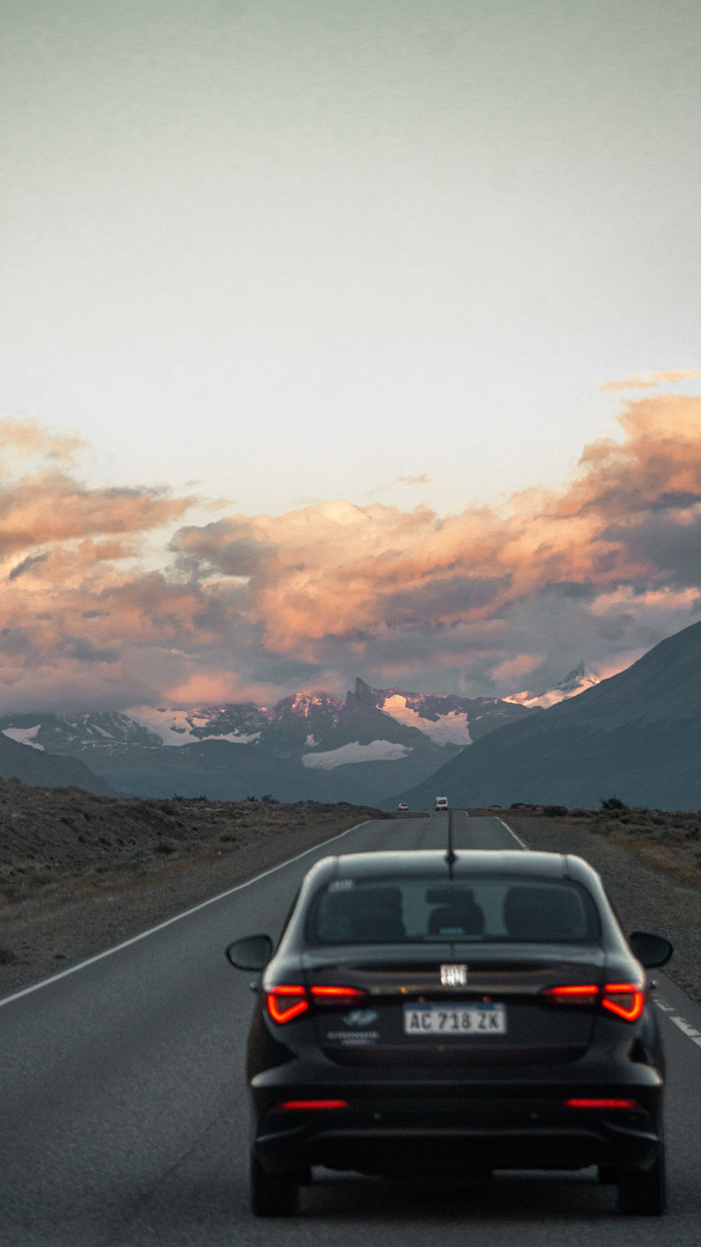 Car driving along a Patagonian road at sunset