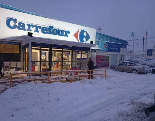 Fachada del supermercado Carrefour de Ushuaia en un día nevado, con cartel azul y rojo