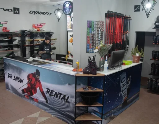Interior de Dr. Snow Rental en Ushuaia con mostrador, esquís y bastones de nieve